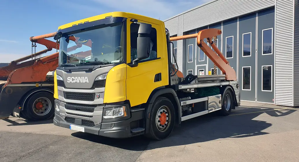 Gul liftdumper parkert utenfor byggning, dette er en tjeneste levert av CoTrack.